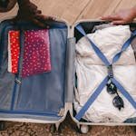 A neatly packed open suitcase with clothing and travel essentials, ready for a trip.