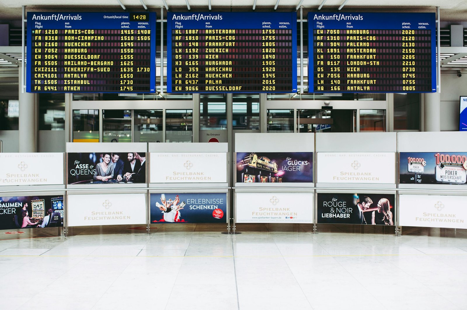 Electronic displays showing flight arrivals at Nuremberg Airport terminal.