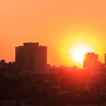 Stunning sunset highlighting silhouetted city buildings with bright orange sky.