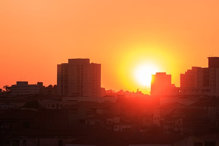 Stunning sunset highlighting silhouetted city buildings with bright orange sky.