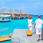 A couple arriving at a luxurious Maldives resort dock with luggage, capturing a tropical vacation vibe. - travel insurance