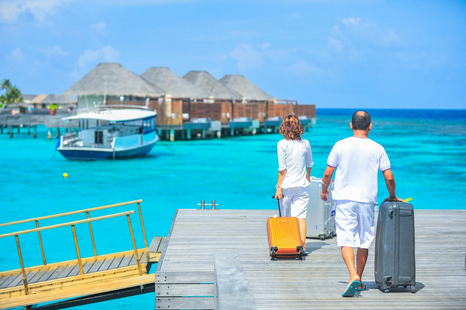 A couple arriving at a luxurious Maldives resort dock with luggage, capturing a tropical vacation vibe. - travel insurance