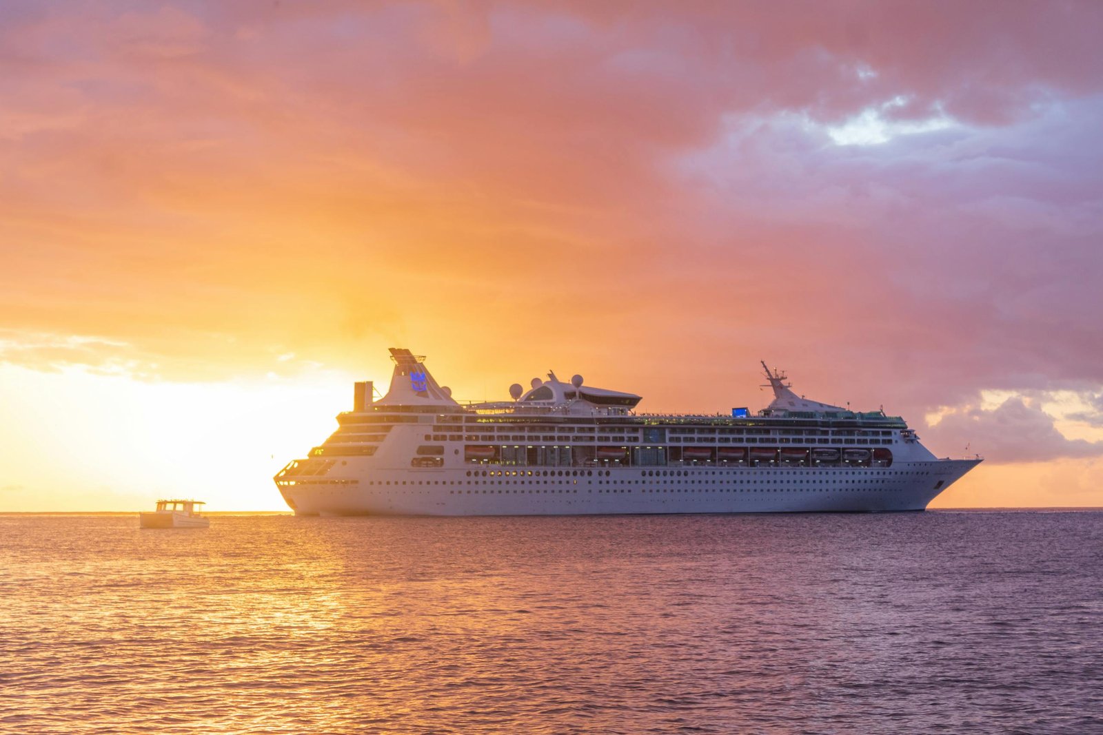 A majestic cruise ship sails at sunset off the coast of Grenada, showcasing luxury travel. Cruise vs Resort