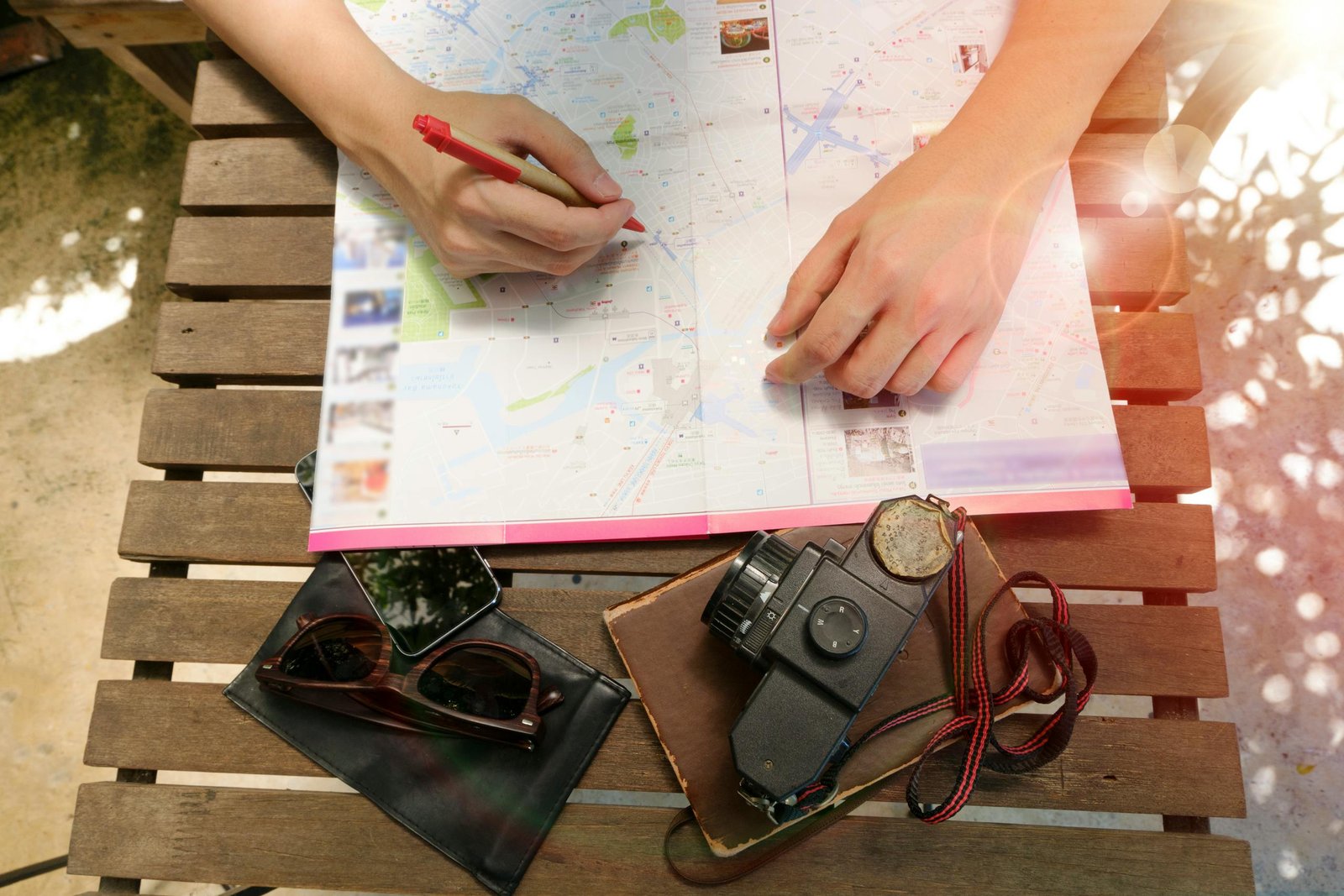 A person planning a journey using a map and vintage camera, evoking travel and exploration. - read travel reviews
