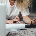 A woman engages in budget planning using a calculator on a comfortable carpeted floor.