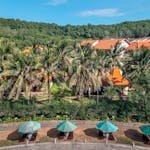 Aerial view of a tropical resort with palm trees and sun umbrellas, perfect for summer vacations. Choose Between All-Inclusive and Independent Travel
