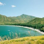 Breathtaking landscape showcasing a serene beach nestled between lush green mountains.