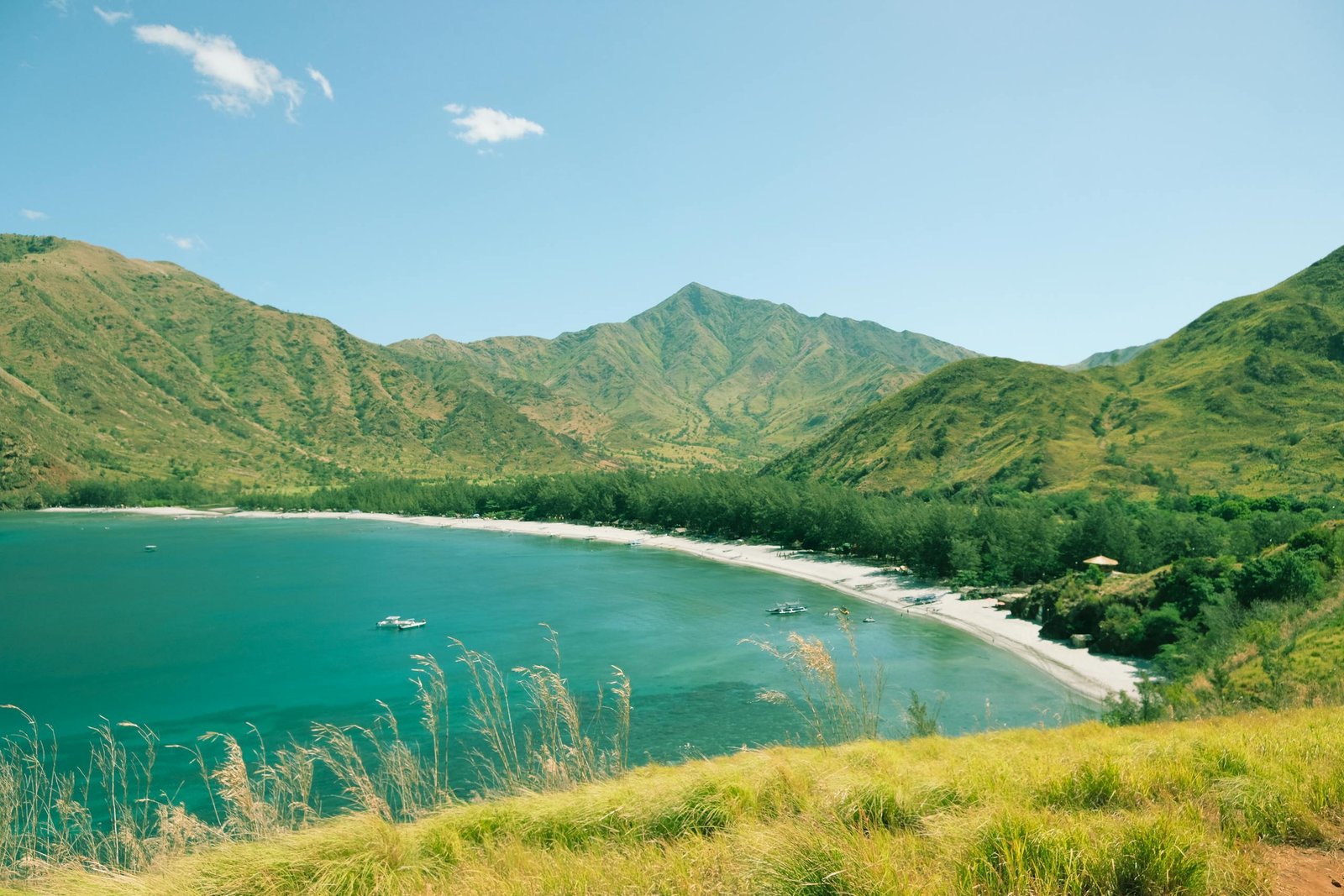 Breathtaking landscape showcasing a serene beach nestled between lush green mountains.