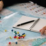 Close-up of hands planning a trip with map, pins, and notebook. travel planning