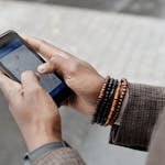 Close-up of hands with bracelets navigating on smartphone using GPS app outdoors. Travel Planning