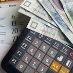 Close-up of Polish Zloty banknotes on a calculator with a calendar in the background. - travel budget