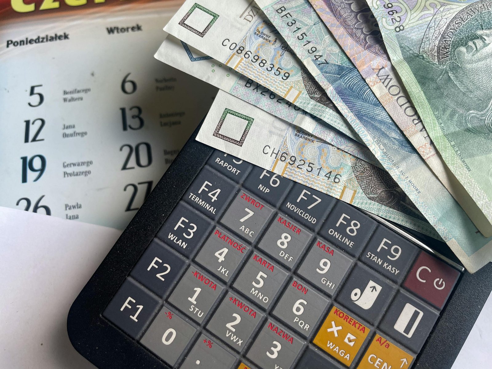 Close-up of Polish Zloty banknotes on a calculator with a calendar in the background. - travel budget
