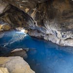Explore the serene blue waters and rugged rock formations of a mysterious cave. - Hidden Gem Destinations