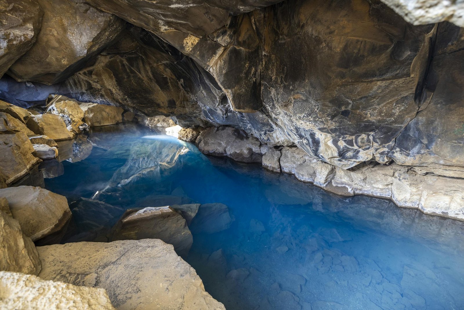 Explore the serene blue waters and rugged rock formations of a mysterious cave. - Hidden Gem Destinations