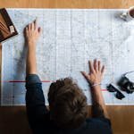 From above composition of stack of USA dollar bills placed near medical protective masks produced in China illustrating concept of medical expenses and deficit during COVID 19