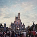 Tourists gather around Cinderella's Castle at Walt Disney World during sunset, capturing a magical moment. - Disney Vacation