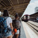 Two backpackers waiting at a railway station, ready for their travel adventure.