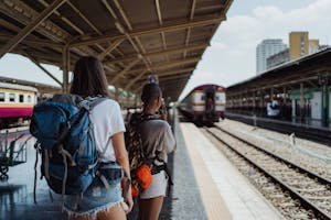 Two backpackers waiting at a railway station, ready for their travel adventure.