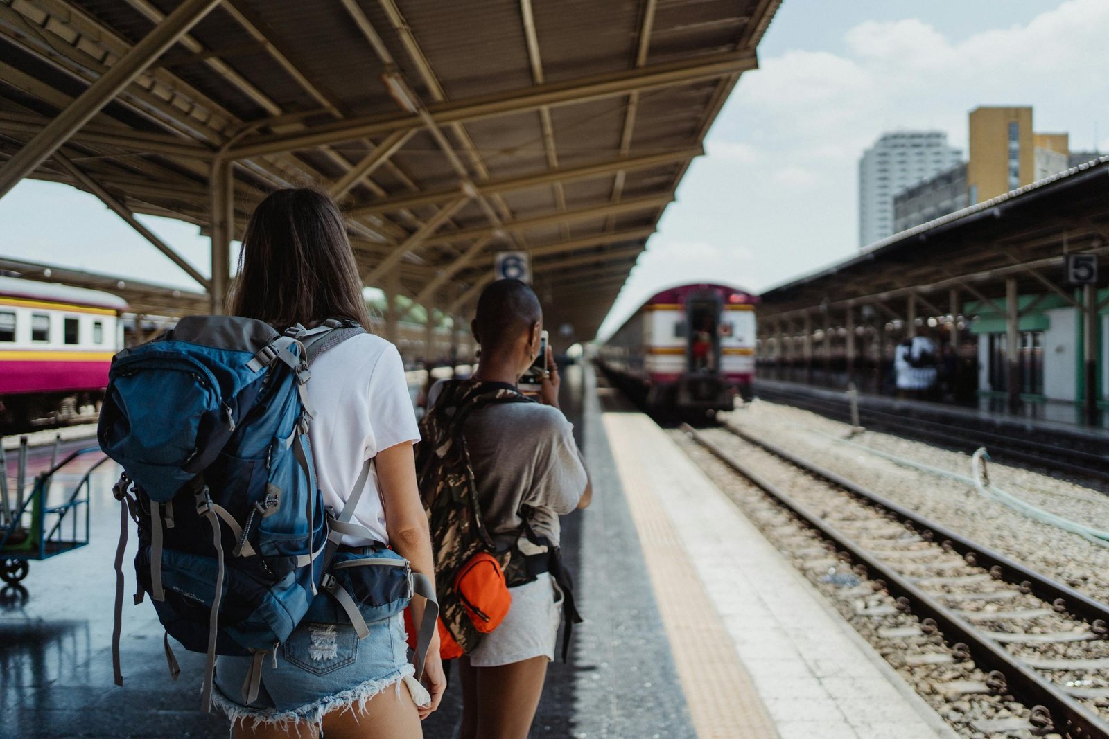 Two backpackers waiting at a railway station, ready for their travel adventure.