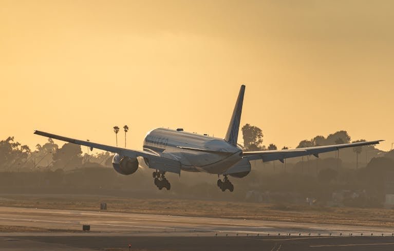 United Airlines aircraft landing at Los Angeles airport runway during a vibrant sunset.