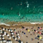 Vibrant summer scene on Antalya's Konyaalti Beach with turquoise waters and colorful umbrellas.