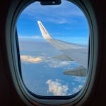View from airplane window showcasing the wing against a sky filled with clouds at high altitude.