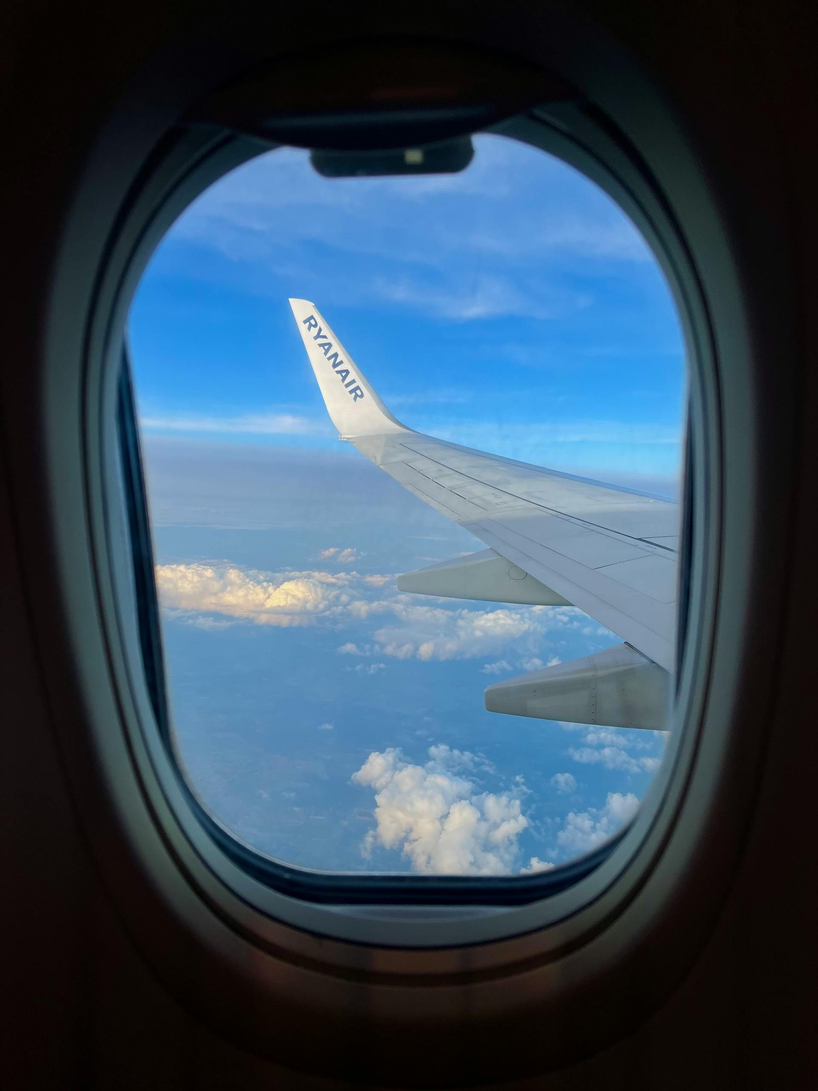 View from airplane window showcasing the wing against a sky filled with clouds at high altitude.