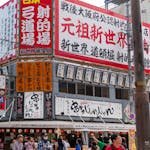 Bustling Osaka street scene with colorful signage, people, and urban architecture. A lively glimpse of Japanese city life.