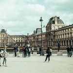 A bustling scene of people walking in front of the iconic Louvre Museum, Paris.