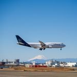 A Lufthansa Boeing 747 landing at an airport with Mount Fuji visible in the background on a clear day.