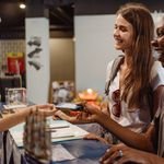 Two women enjoying a cheerful check-in at a hostel reception desk.